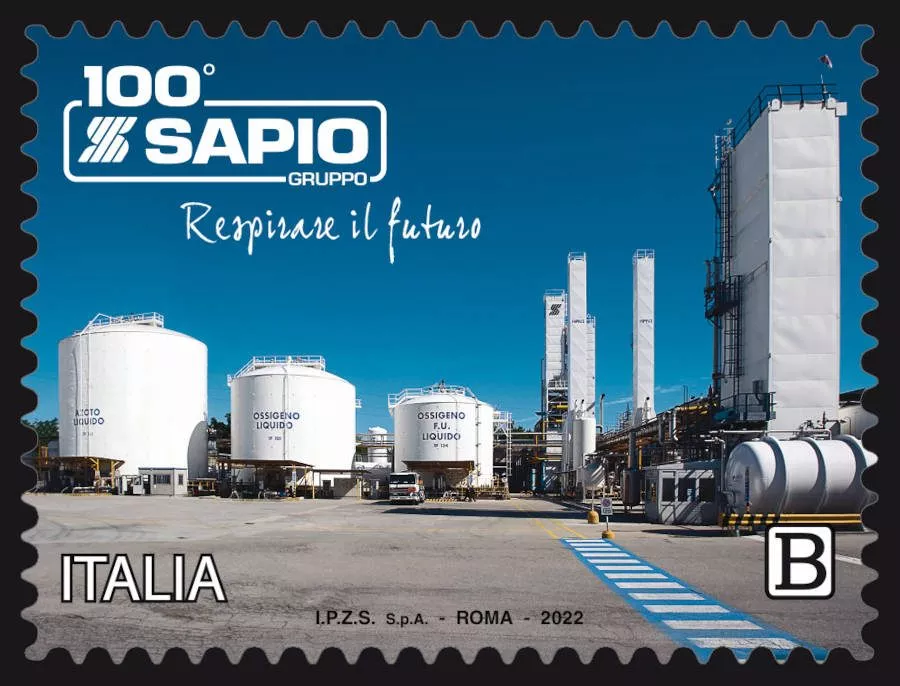 Francobollo italiano commemorativo dei 100 anni del Gruppo Sapio, raffigurante una veduta di un impianto industriale con grandi serbatoi di stoccaggio bianchi etichettati "Ossigeno Liquido" e alte torri di raffineria sotto un cielo azzurro. Il testo recita "Respirare il futuro" e "Italia.