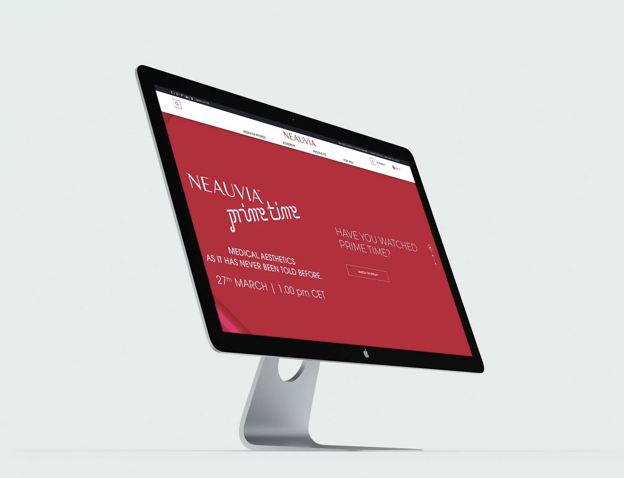 Un elegante monitor desktop mostra un sito Web con uno sfondo rosso. Il testo sullo schermo recita "NEAUVIA prime time. HAI GUARDATO PRIME TIME? NEAUVIA ESTETICA COME NON È MAI STATA RACCONTATA PRIMA. 27 MARZO | 13:00 CET." Il monitor è impostato su uno sfondo semplice, grigio chiaro.